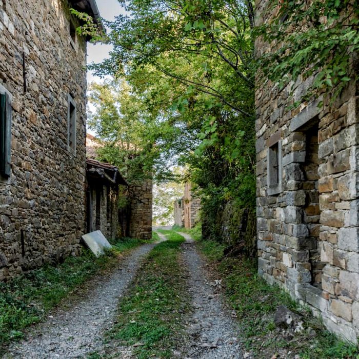 Una stradina bianca passa tra due costruzioni di pietra nel borgo di Palagano