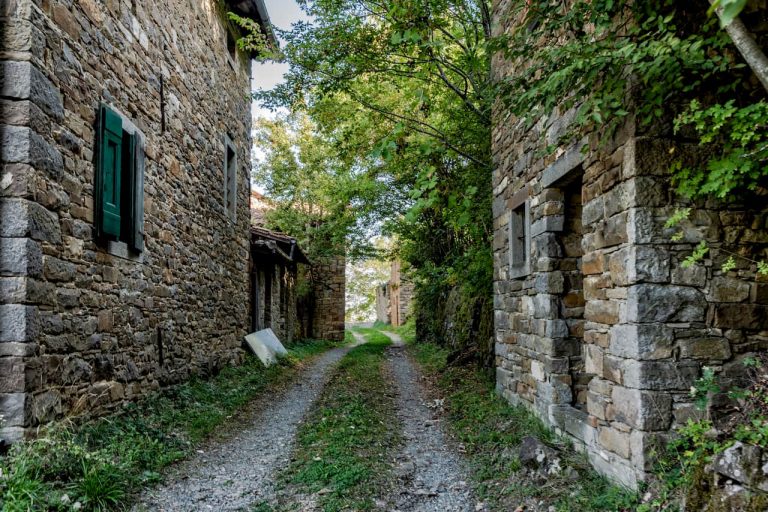 Una stradina bianca passa tra due costruzioni di pietra nel borgo di Palagano